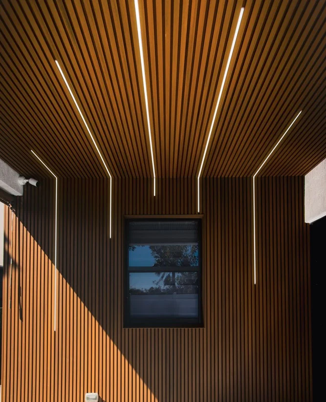 Timber-slat cladding wrapping a wall and soffit, with linear lighting recessed between the battens